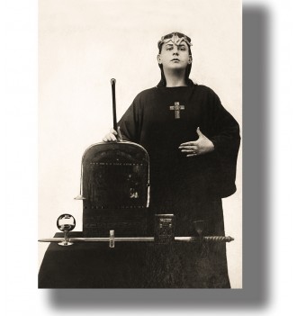 Vintage photo of Aleister Crowley in ritual robes standing by an altar with occult objects.