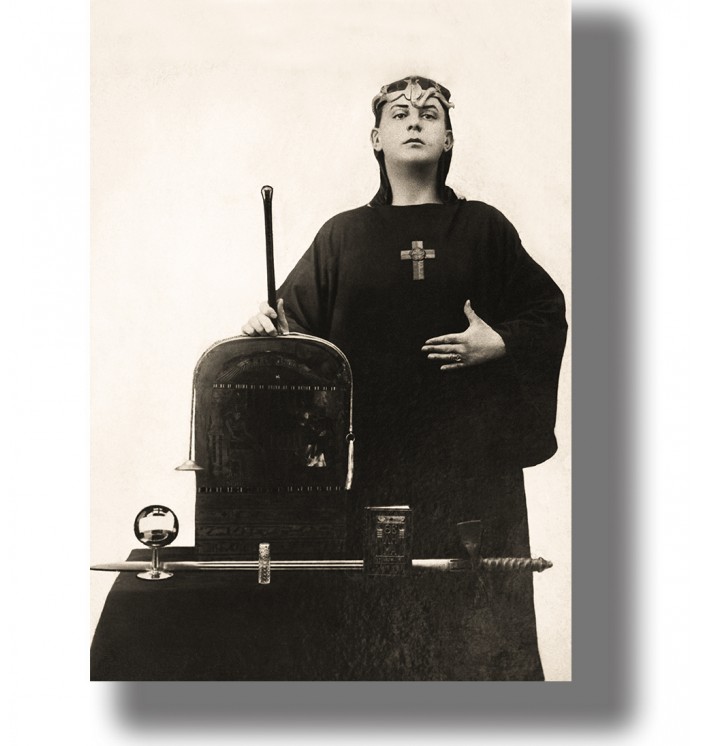 Vintage photo of Aleister Crowley in ritual robes standing by an altar with occult objects.