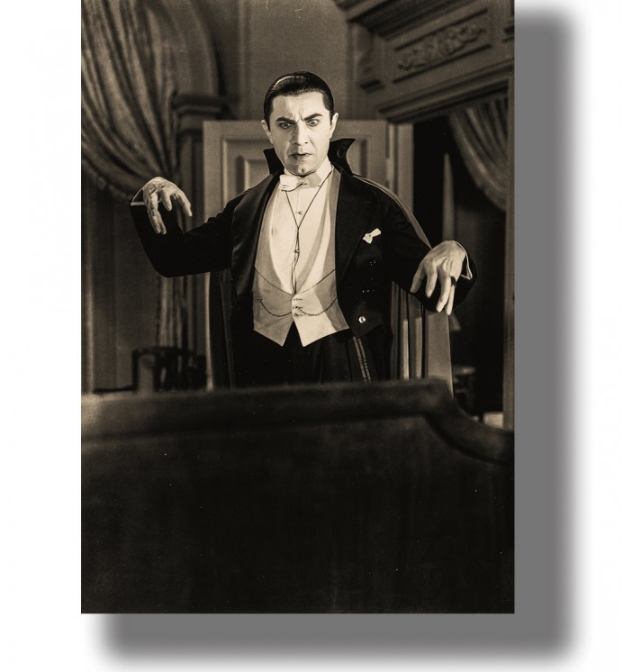 Bela Lugosi as Dracula in a black and white movie scene, standing in a dark room with raised hands.
