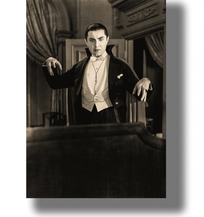 Bela Lugosi as Dracula in a black and white movie scene, standing in a dark room with raised hands.