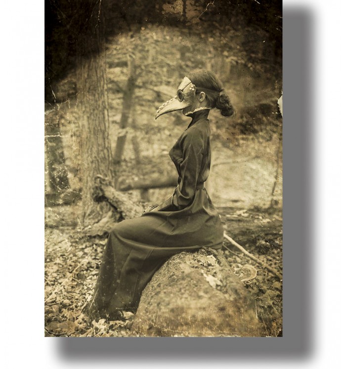 Vintage-style image of a person in a plague doctor mask sitting on a rock in the woods.