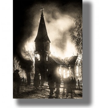 Black and white photo of a church burning at night, with flames, smoke, and people standing nearby.