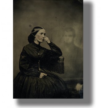 Old Victorian-style photo of a woman seated in black dress with a faint ghostly figure behind her.