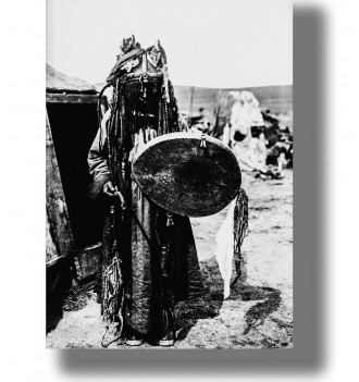 Mongolian shaman in traditional ritual clothing holding a large ceremonial drum in a vintage black and white photograph.